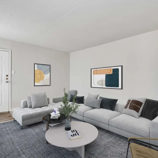 Carpeted furnished living area with central air and hallway leading to bedroom at Dallas, TX apartments