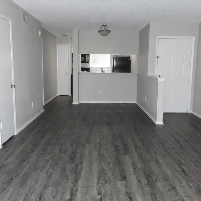 The living room facing the kitchen and entrance on hardwood-style flooring. 