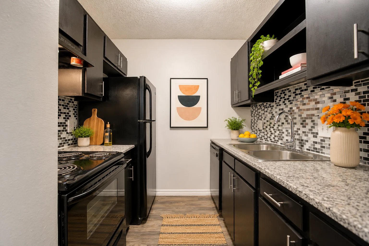 Stylish Modern Kitchen Interior A modern kitchen with black cabinetry, stainless steel appliances, and a stylish backsplash. There are plants on the shelves and a vase of orange flowers on the countertop. A framed art piece is hanging on the wall.