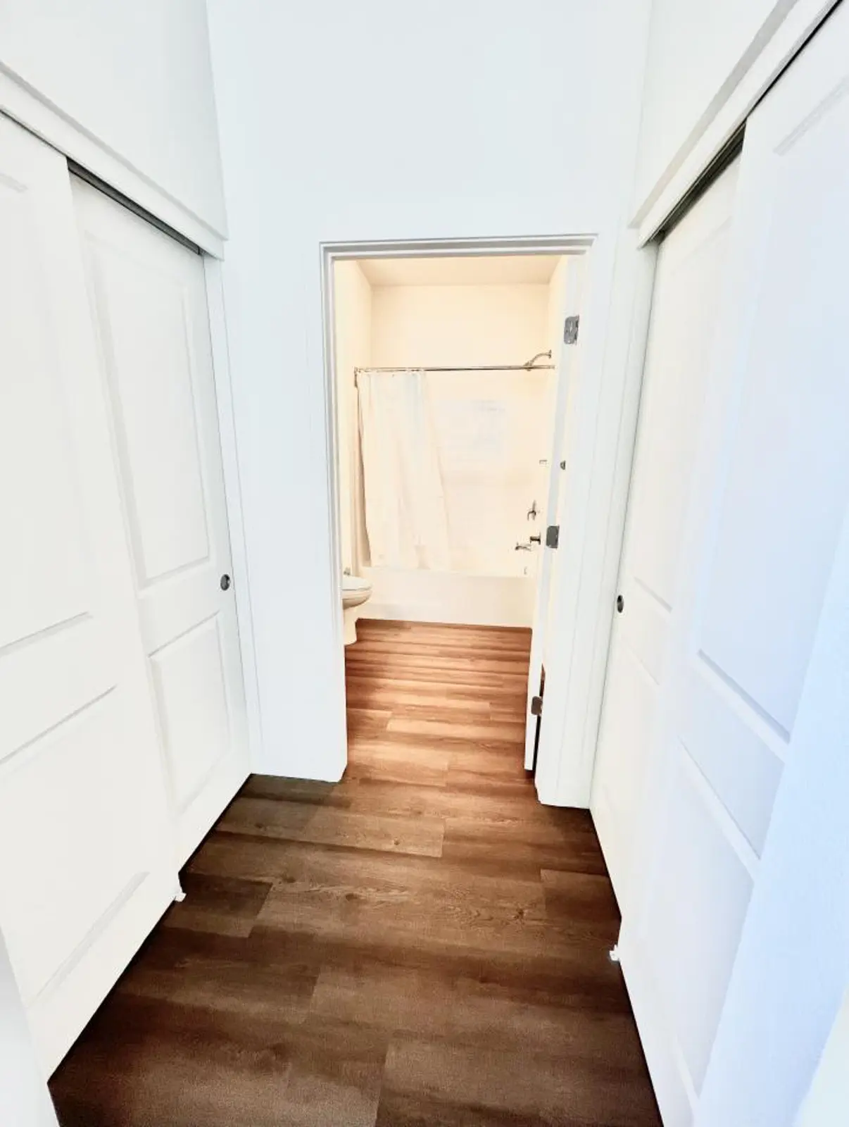 Hallway leading to a bathroom with a tub and shower curtain.
