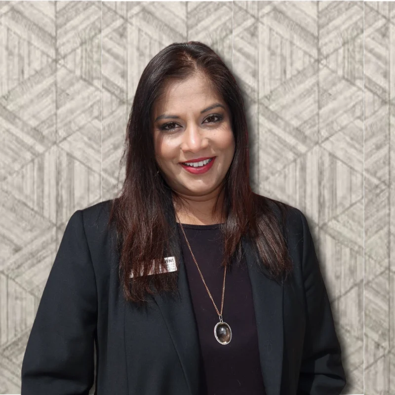Professional Portrait in Geometric Design A smiling woman in a black blazer stands in front of a geometric patterned wall.