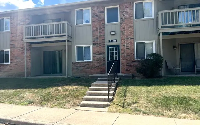 Apartment Building Exterior Front view of a two-story apartment building with multiple units and steps leading up to the entrance.