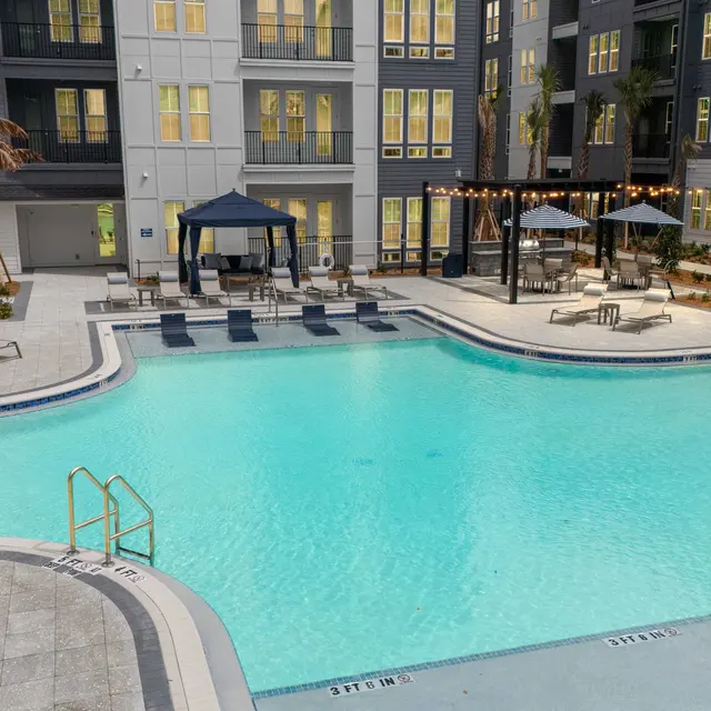 Apartment Pool Area A bright and inviting swimming pool area surrounded by modern apartment buildings, featuring lounge chairs and shaded cabanas.