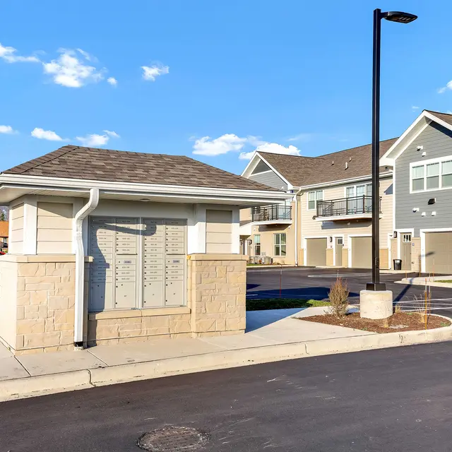 A community mailbox area situated near an apartment complex with several buildings and a clear blue sky.