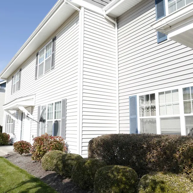 Exterior view of a residential apartment building with white siding and landscaping.