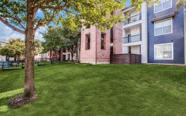 View of an apartment complex with green lawn and trees