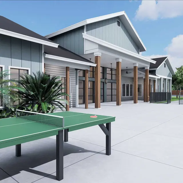 Outdoor area featuring a ping pong table, swimming pool, and modern buildings surrounded by greenery and a clear blue sky.
