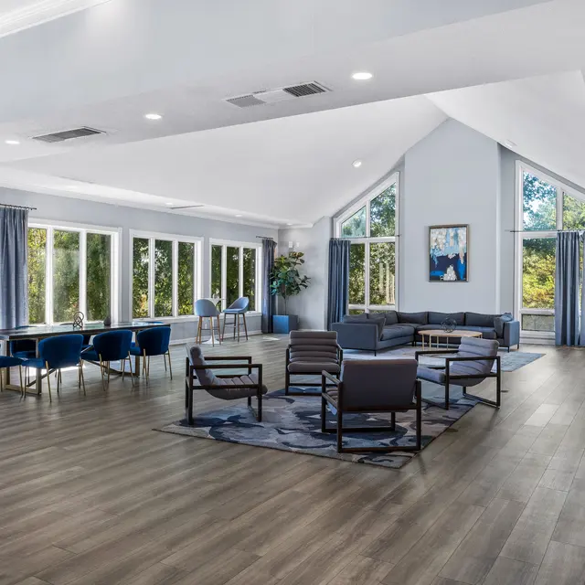 Spacious Modern Living Area A spacious modern living area with large windows featuring blue curtains, a dining table with blue chairs, and seating arrangements in gray.