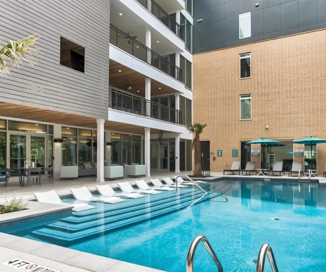 Outdoor resort-style swimming pool with lounge chairs and table umbrellas surrounding the pool at 120 Ninth Street.