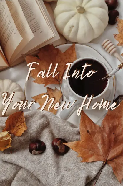 Fall Into Your New Home A cozy autumn scene featuring a cup of coffee, an open book, decorative pumpkins, and fall leaves on a table.