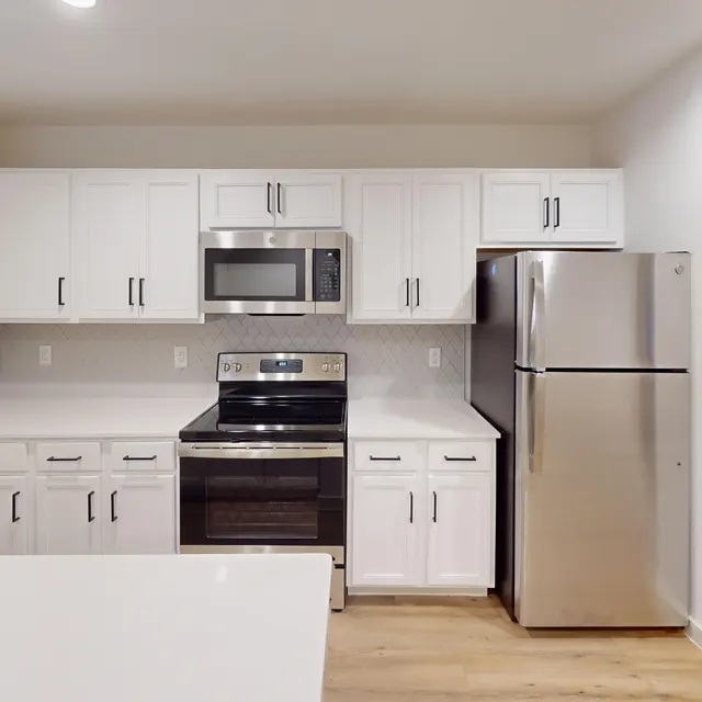 A modern kitchen featuring white cabinets, stainless steel appliances, and a granite countertop.