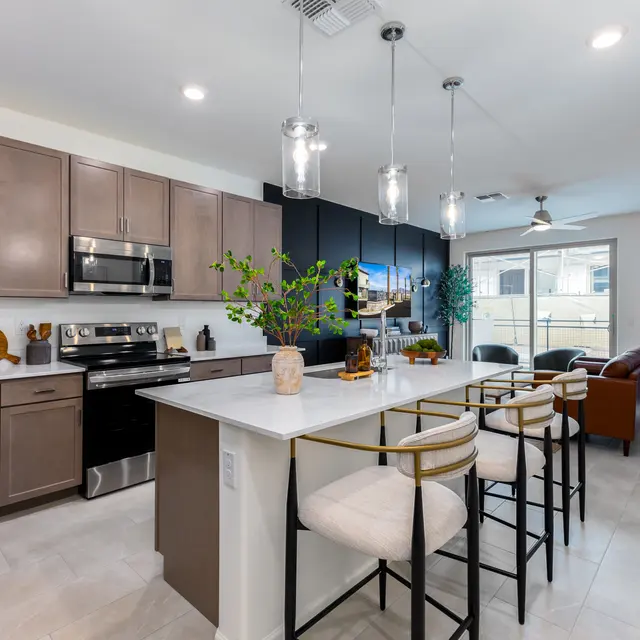 A modern kitchen with dark and light cabinetry, an island with seating, and stainless steel appliances.