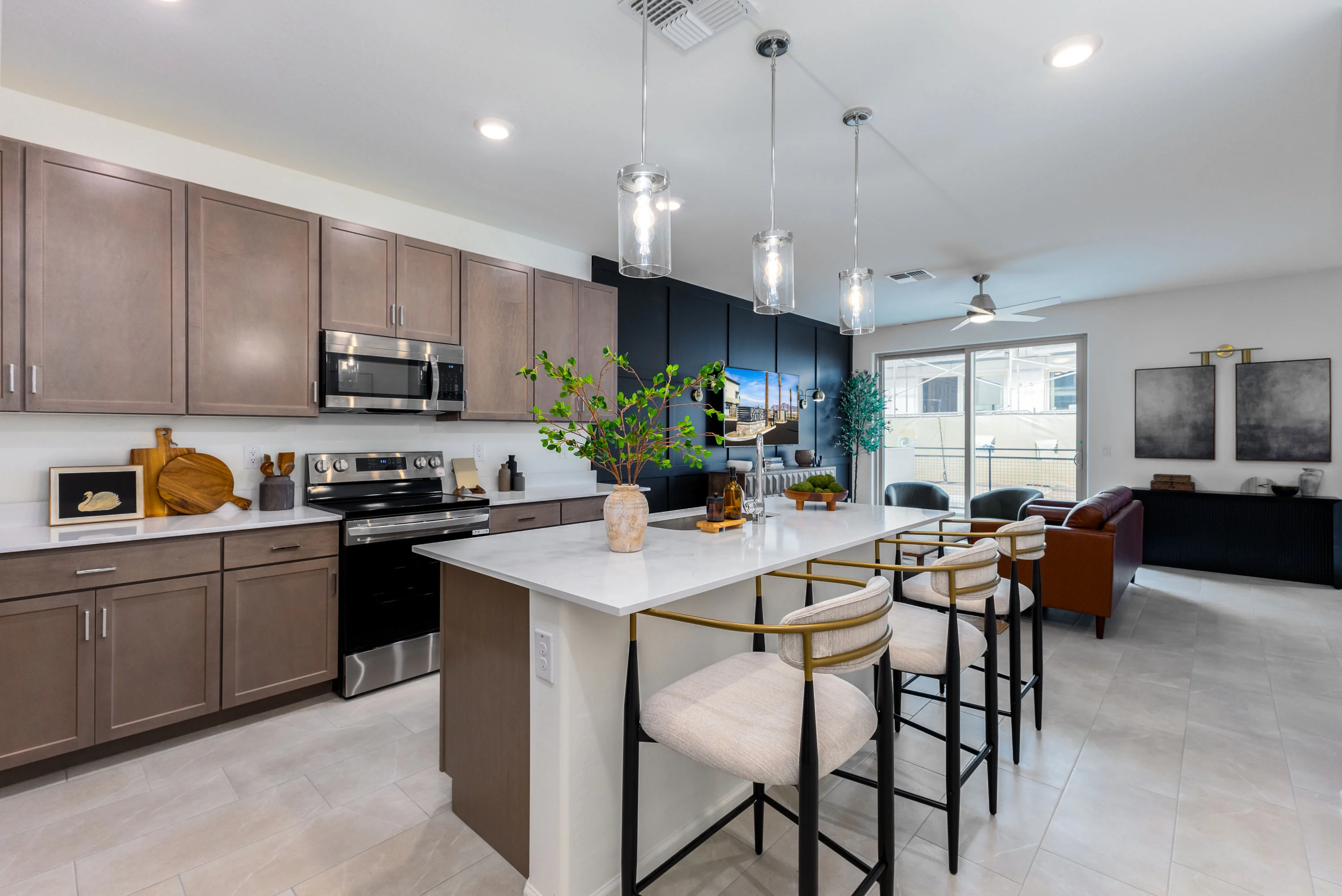 A modern kitchen with dark and light cabinetry, an island with seating, and stainless steel appliances.