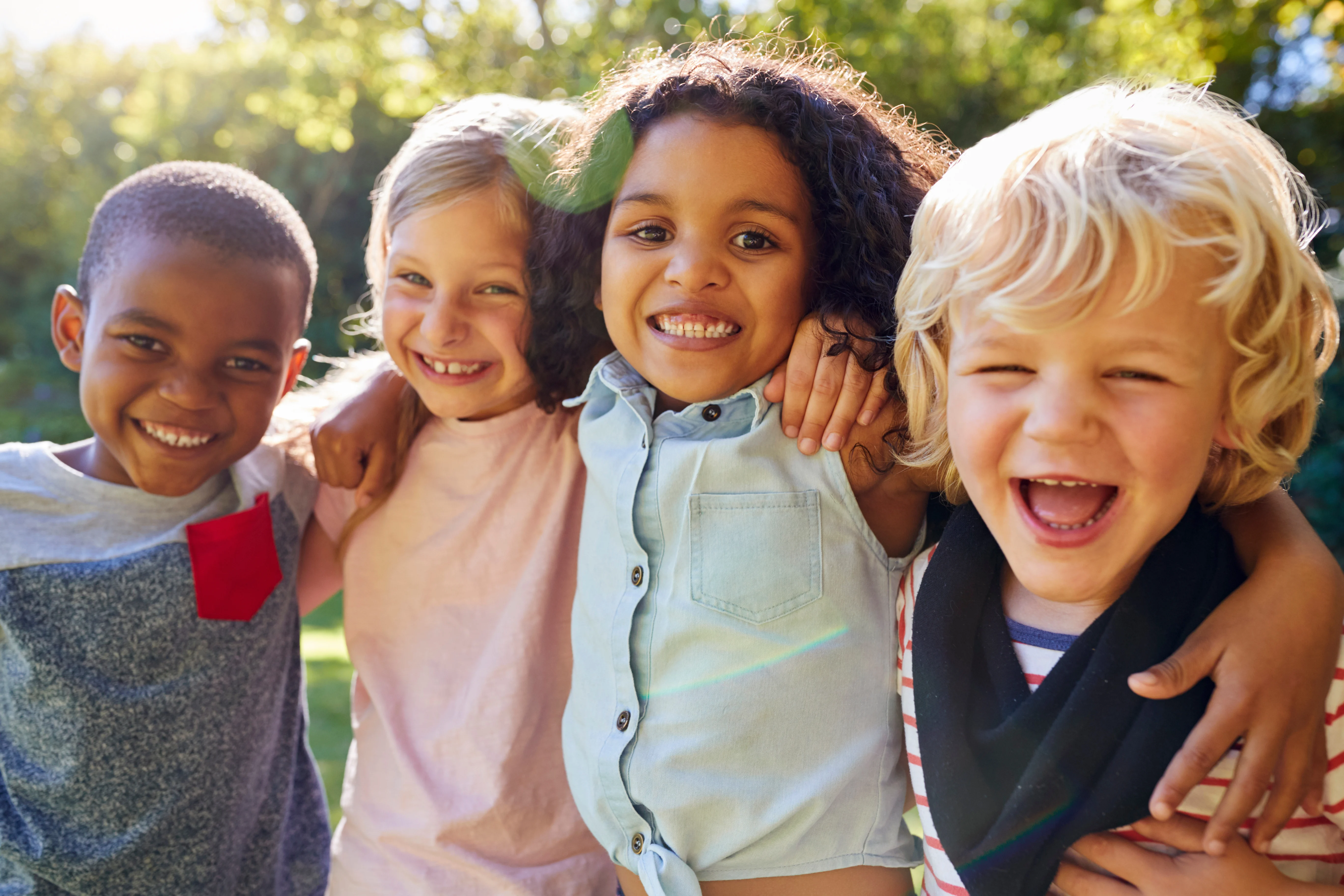 Happy Children Outdoors A diverse group of four children smiling and posing together outdoors, showing happiness and friendship.