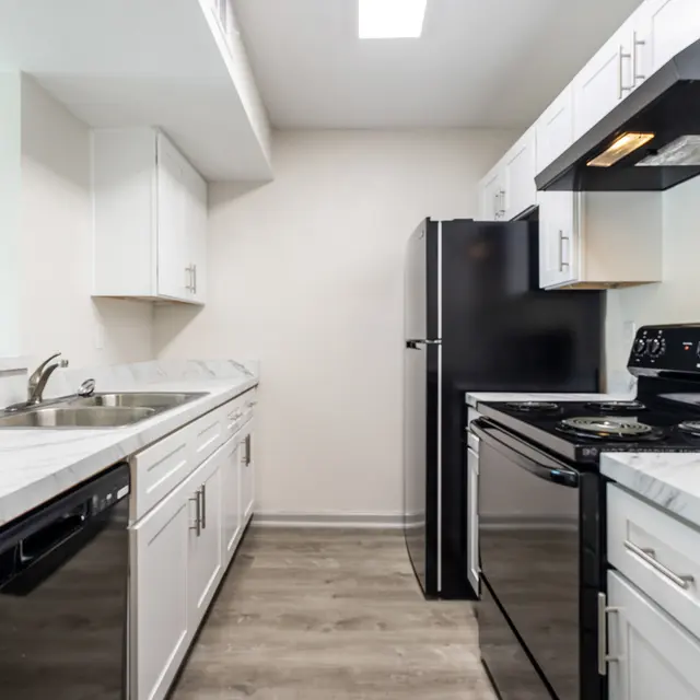 A modern kitchen featuring white cabinets, stainless steel appliances, and a clean layout with a dark grey refrigerator and stove.