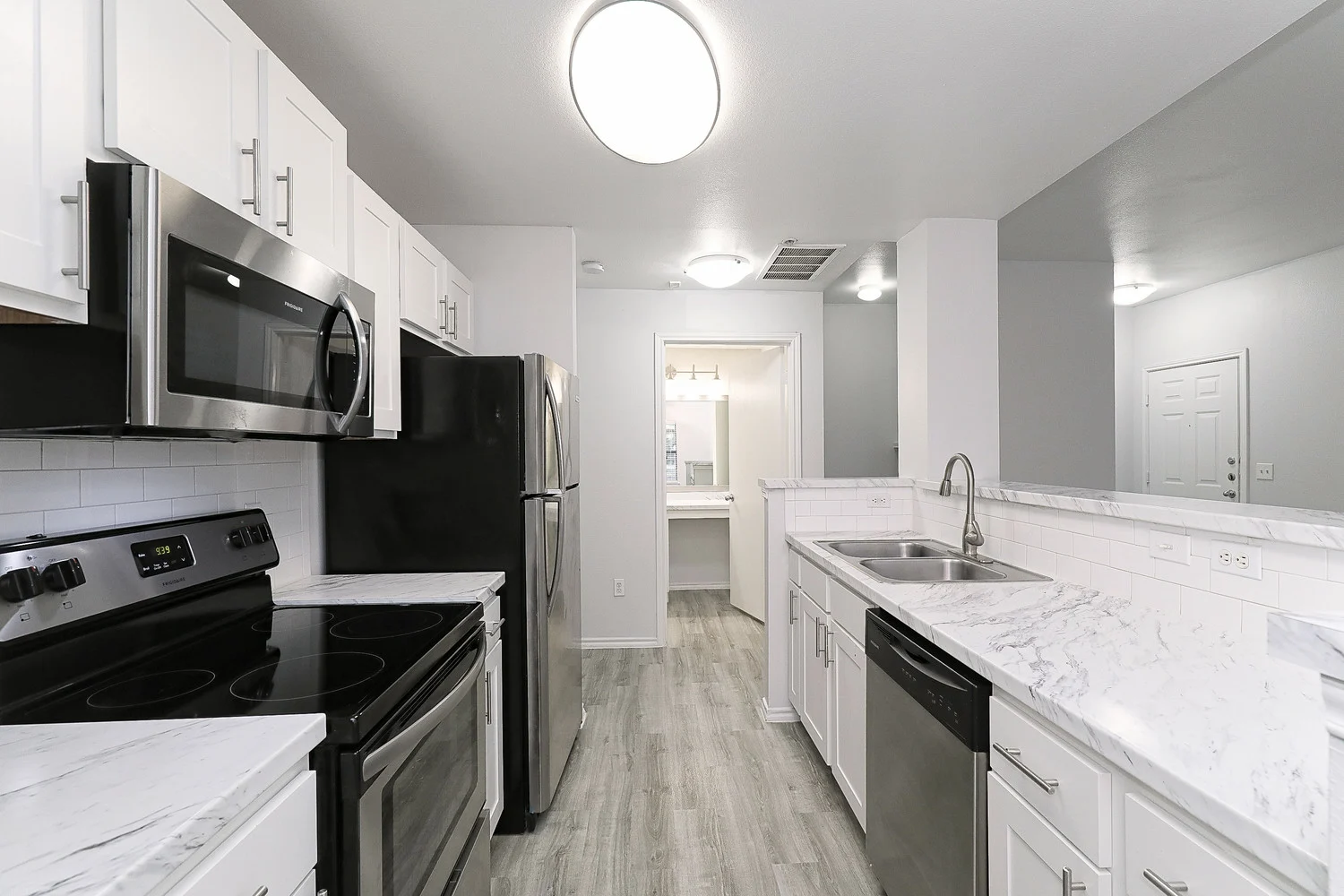 Brywnood Apartments Modern kitchen with white cabinetry, stainless steel appliances, marble countertops, and a spacious layout.