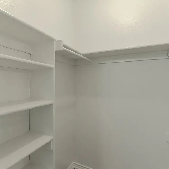 An empty closet with white walls and shelving.