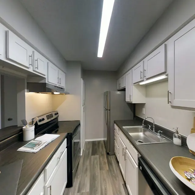 Kitchen with white cabinets, stainless steel appliances, and a countertop with an open window concept facing the living room. 