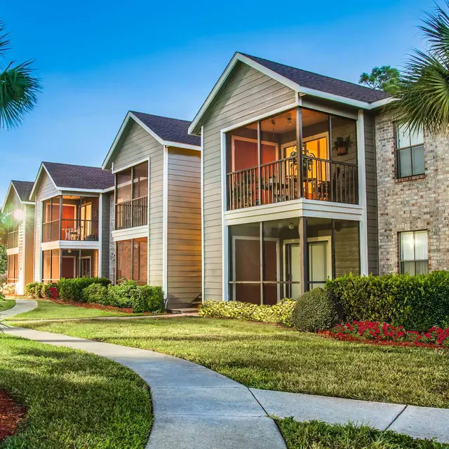Venice Park exterior with balconies and a sidewalk surrounded by grass and trees.