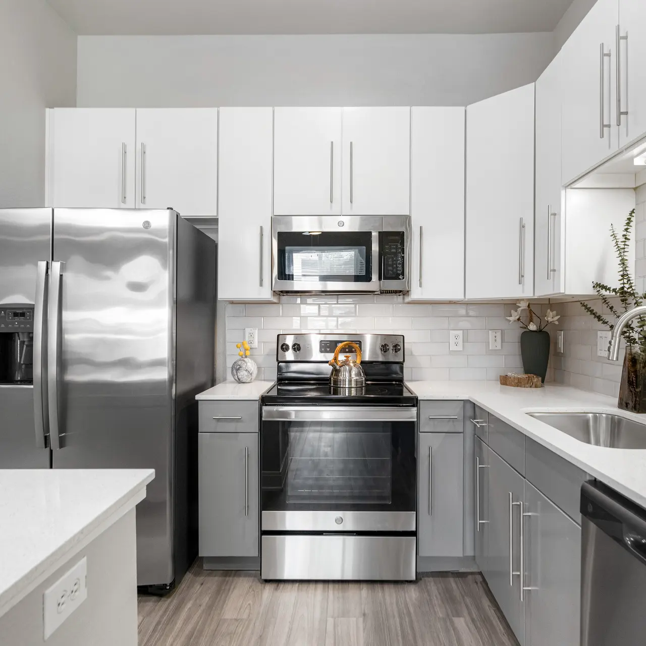 A modern kitchen featuring stainless steel appliances, white cabinets, and a sleek countertop.
