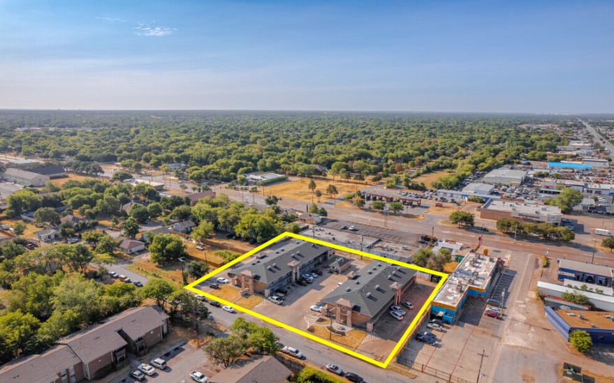 Aerial view of a commercial property outlined in yellow, surrounded by greenery and urban areas.