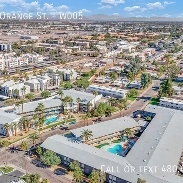 Aerial view of a residential area featuring several apartment complexes, streets, and greenery.