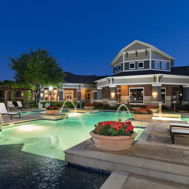 Centreport Lake Community pool at night with pool lights on with trees and plant gardens surrounding the pool.