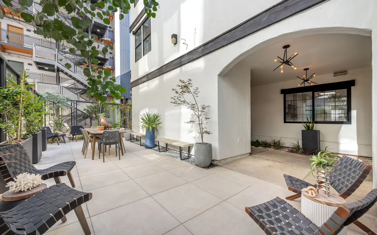 A modern courtyard with a seating area and dining table surrounded by plants.