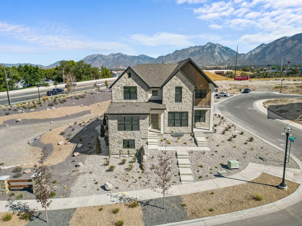 Modern Stone House with Mountain Views A modern stone house with a triangular roof surrounded by gravel landscaping and mountains in the background.