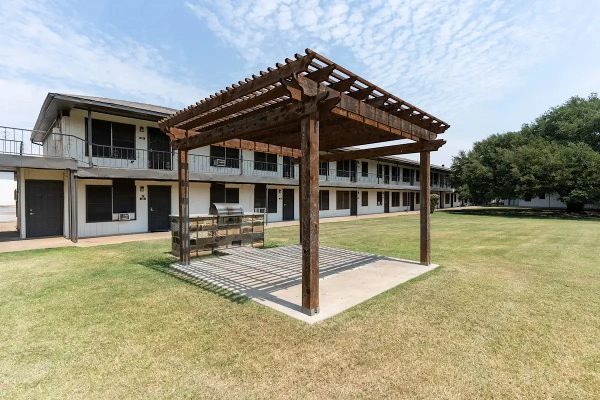 Pergola at Apartment Complex An outdoor pergola structure in front of a two-story apartment complex with grassy areas.