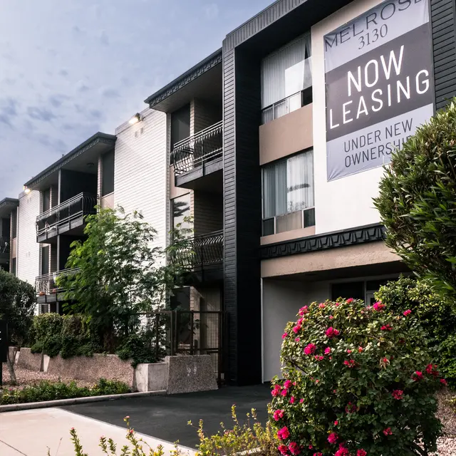 Exterior view of an apartment building with 'Now Leasing' sign