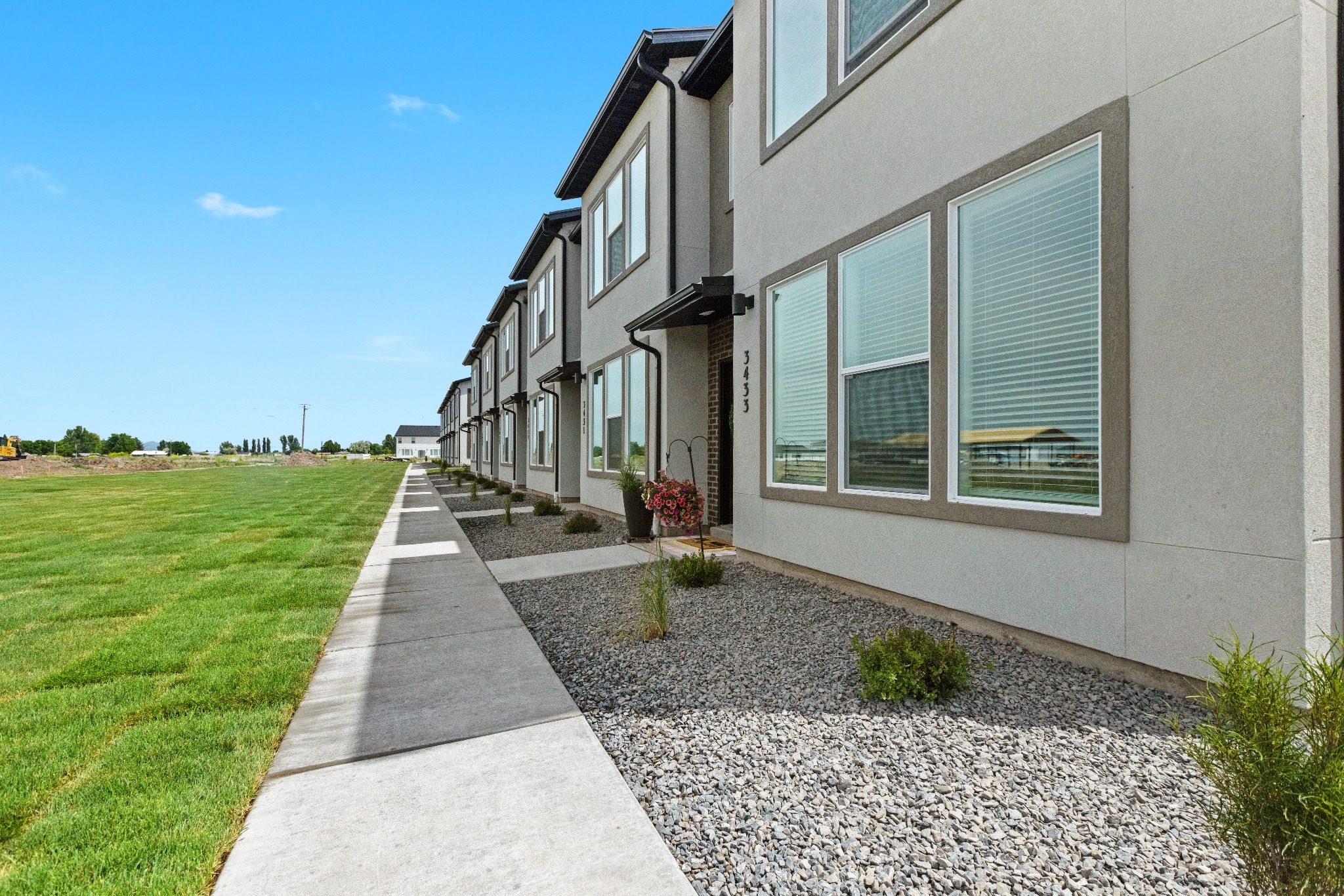 Exterior view of a row of modern apartment buildings with green grass and walking path.