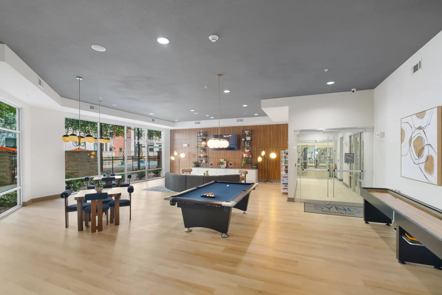 Modern community space featuring a pool table, seating area, and large windows.