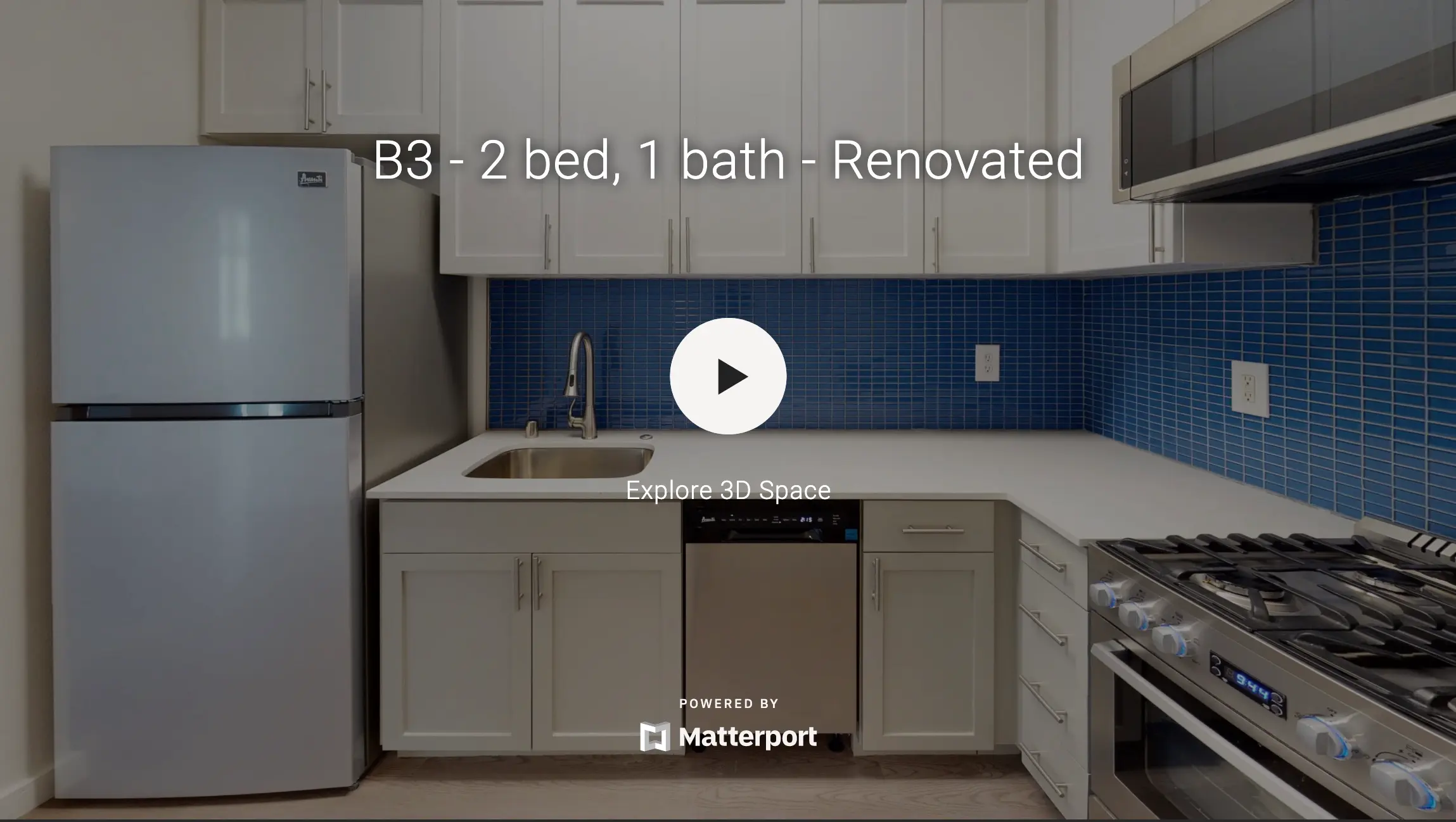 Modern kitchen in a renovated apartment featuring a refrigerator, sink, and stove with a blue tiled backsplash.