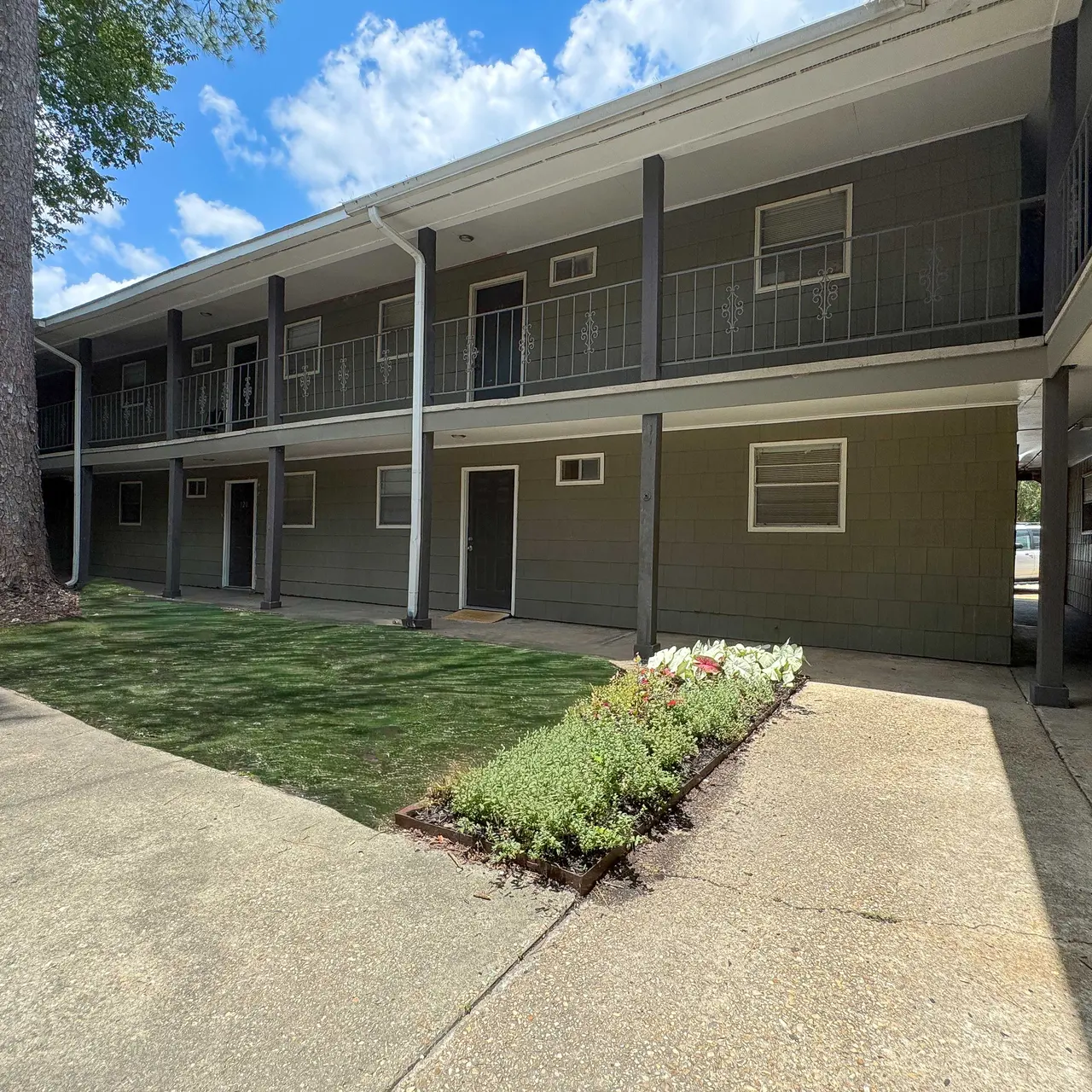 Two-story apartment building with balconies and a grassy courtyard.