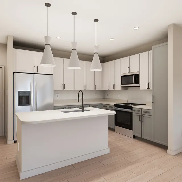 A modern kitchen featuring white cabinetry, stainless steel appliances, and a central island with a sink, illuminated by pendant lights.