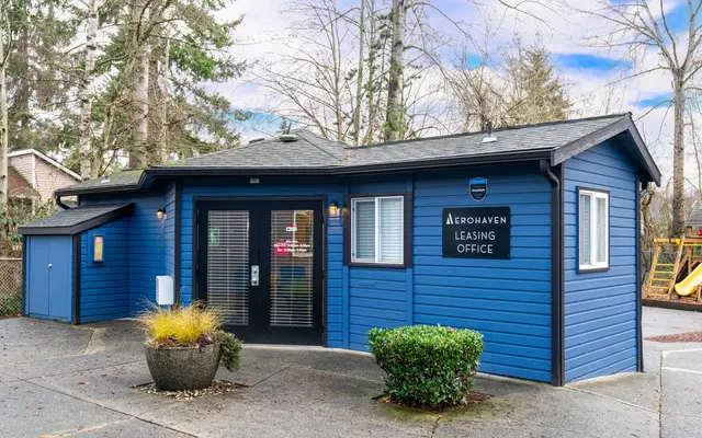 A blue leasing office building surrounded by trees, featuring a sign that reads 'Aerohaven Leasing Office.'