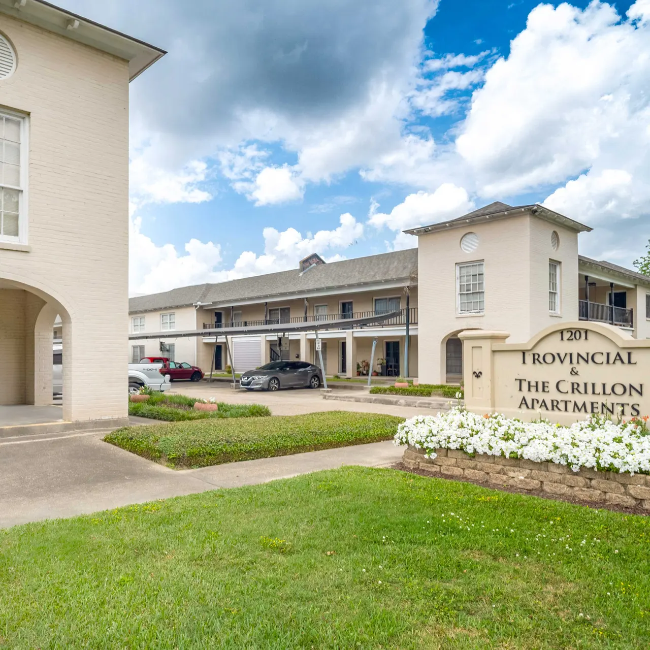 Exterior view of The Grillon Apartments with a sign and landscaped area in front.