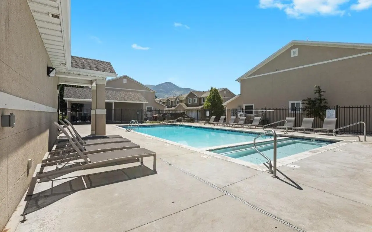 Swimming Pool Area with Mountain Views A swimming pool area featuring lounge chairs, a clear blue sky, and mountains in the background.