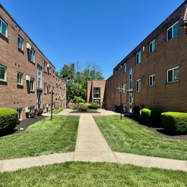 Sunny Apartment Complex View of a brick apartment complex with well-maintained grassy areas under a clear blue sky.