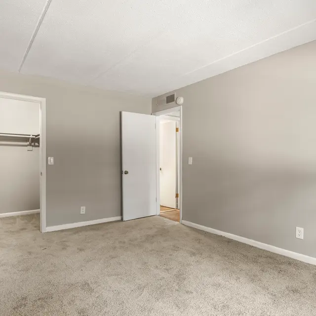Neutral-toned bedroom with carpeted floors and open closet door at Alderman Park in the Southside neighborhood of Jacksonville