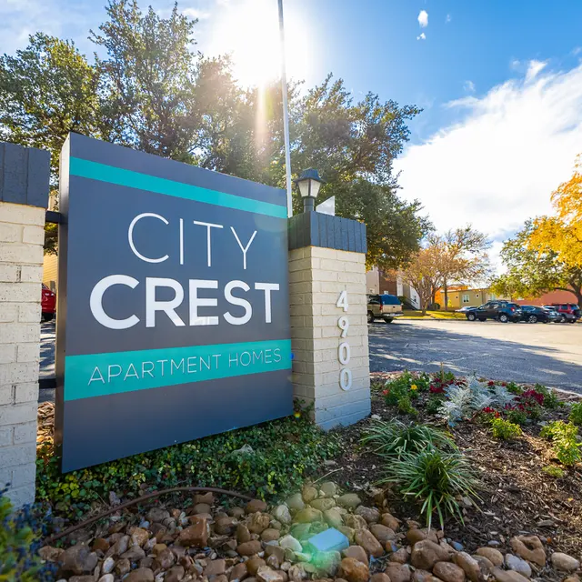 Sign for City Crest Apartment Homes near a residential area with trees and a clear sky.