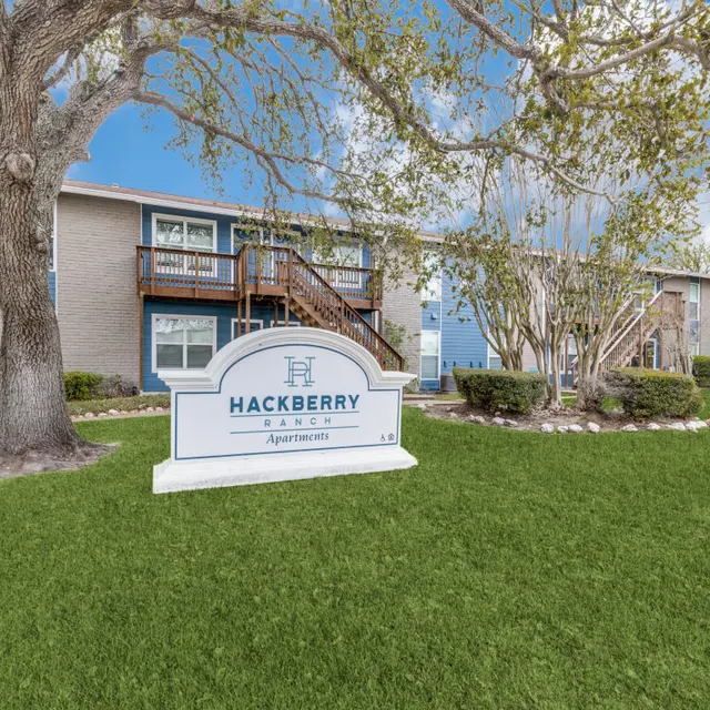 Exterior view of Hackberry Apartments with a sign in front and a well-maintained landscape.