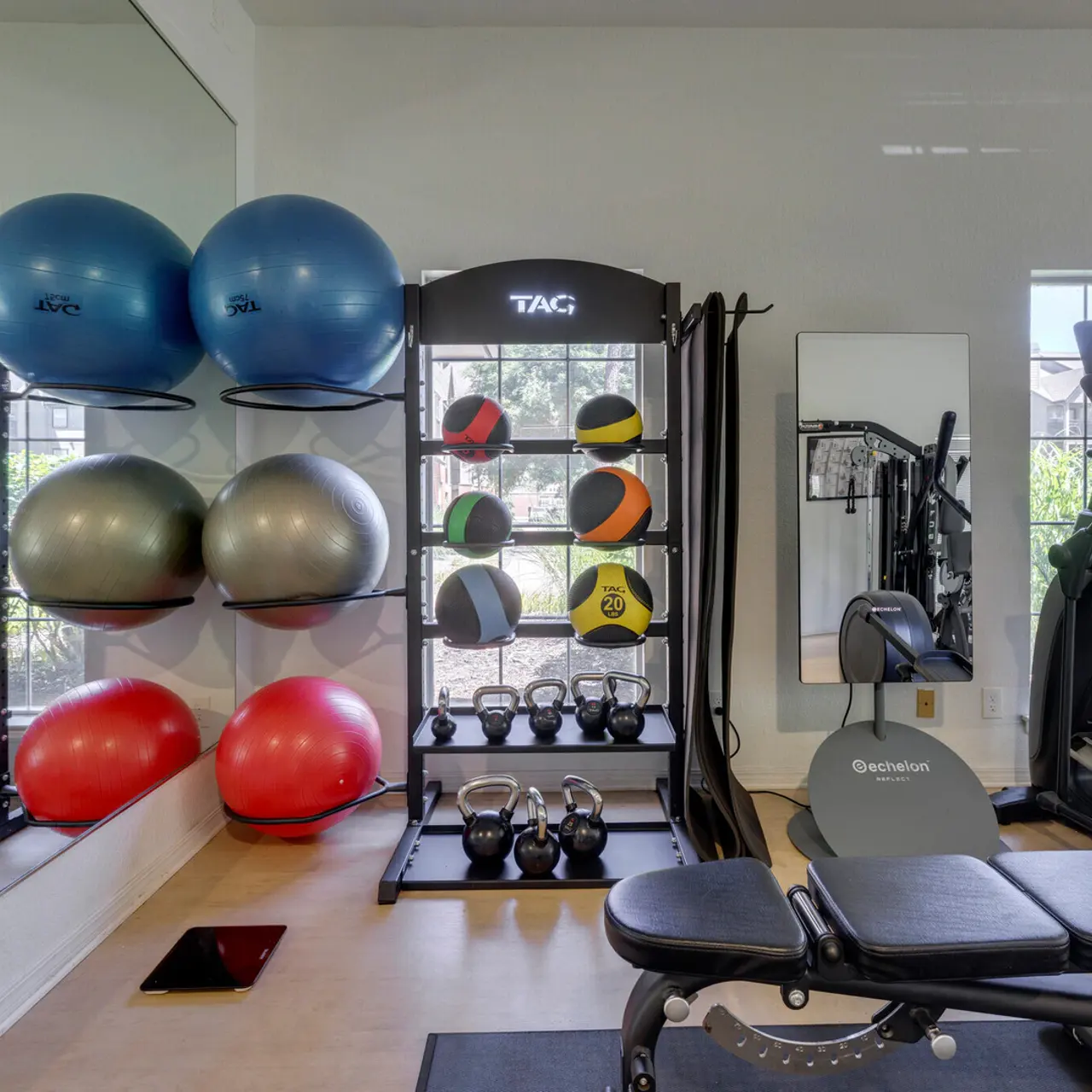 Modern Home Gym with Exercise Equipment A modern home gym featuring various exercise equipment including fitness balls, kettlebells, an elliptical machine, and a workout bench.