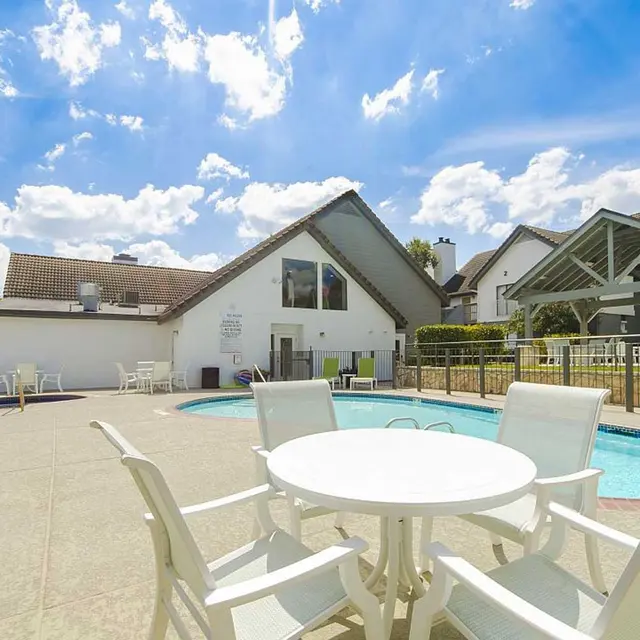 Patio table and four chairs at pool lounge area at Edge Studios apartments in San Antonio