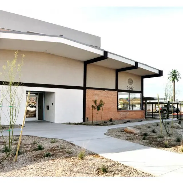 Modern Building Exterior A modern building exterior with a smooth entrance path, featuring a clean architectural design, minimal landscaping, and a visible address number on the wall.