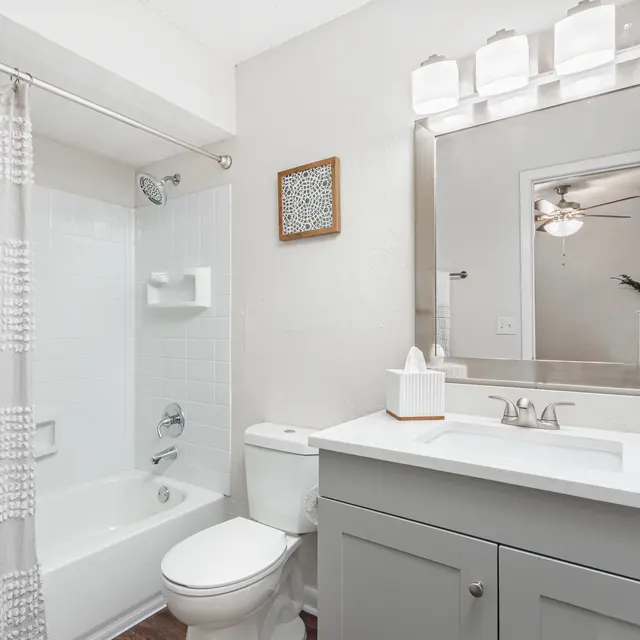 Bathroom with off-white walls, over-sink lighting, and a bathtub with tiled walls in Jacksonville, FL apartments.