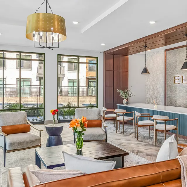A modern lobby with stylish seating, a coffee table, and large windows showcasing outdoor greenery. The reception area features a contemporary design with a welcoming atmosphere.