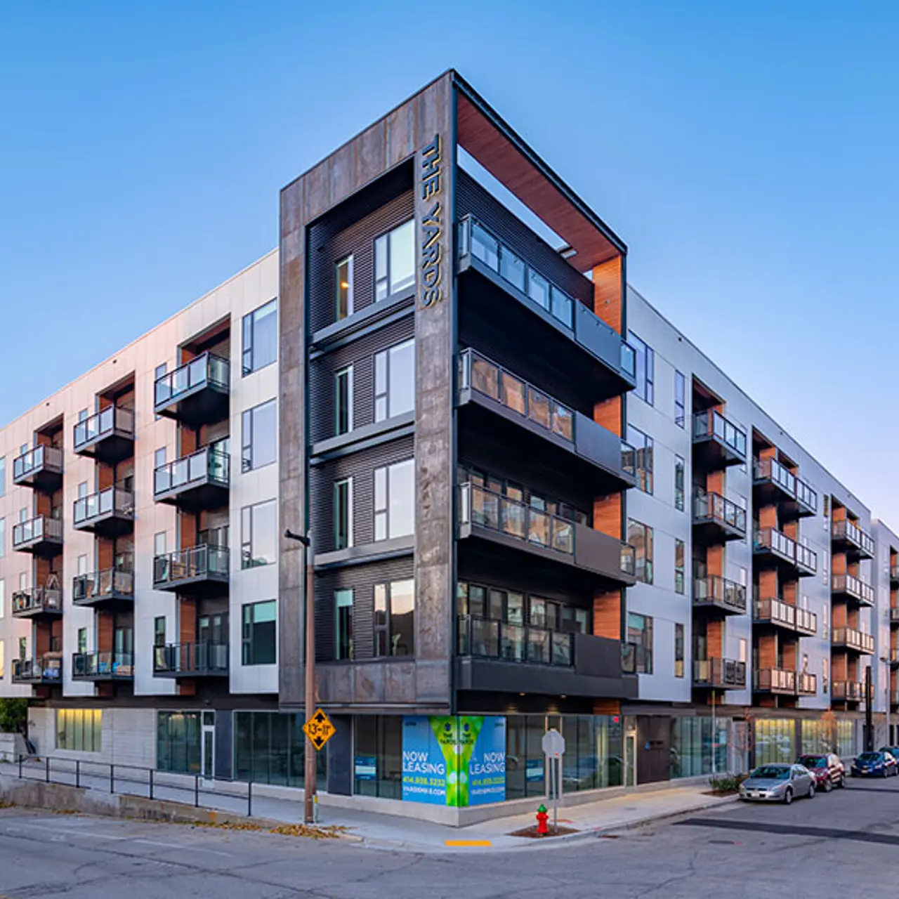 Urban Apartment Building A modern multi-story apartment building with a stylish facade, featuring balconies and large windows, set against a clear blue sky.