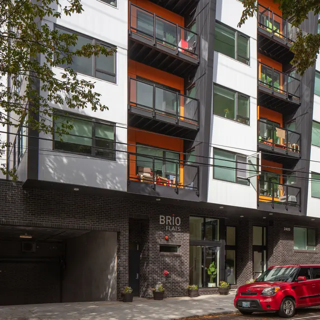 Brio Place Apartment Building Modern apartment building with a mix of white, black, and orange exterior and balconies.